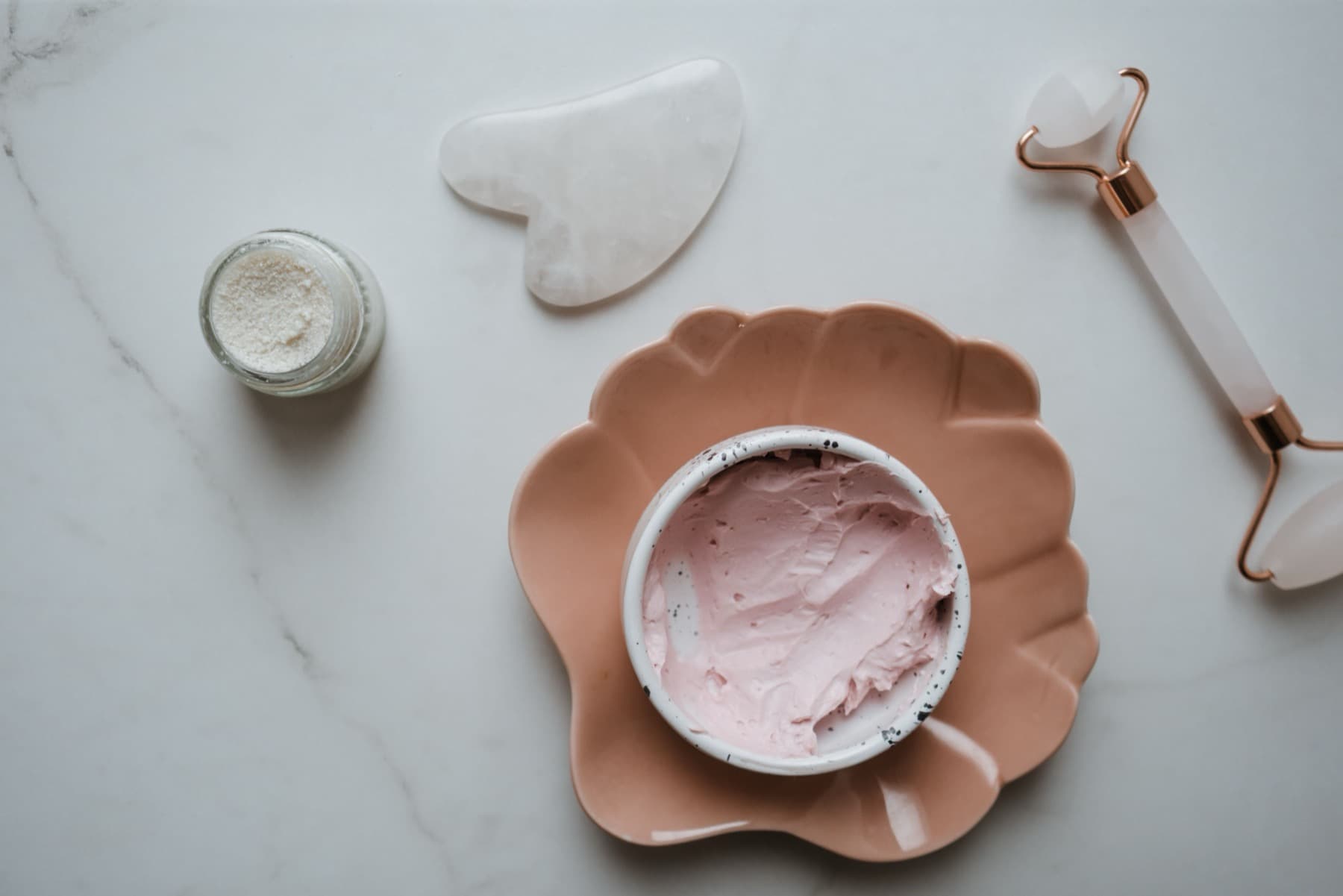 Skincare textures and facial tools on a marble surface